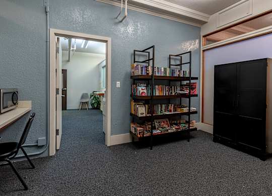 A room with a bookshelf filled with books and a television on the right side.