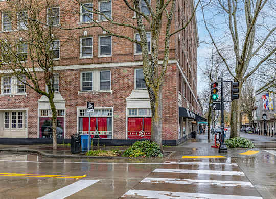 A crosswalk in front of a brick building with a red awning.