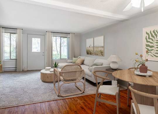 A living room with a white couch, a wooden table, and a rocking chair.