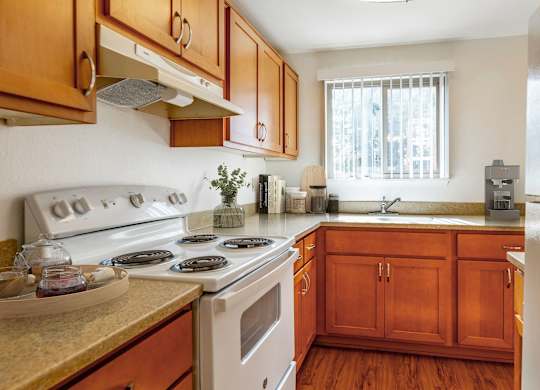 A kitchen with wooden cabinets and a white stove top.