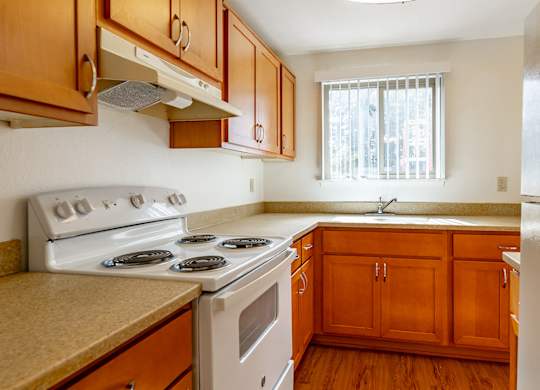 A kitchen with wooden cabinets and a white stove top oven.