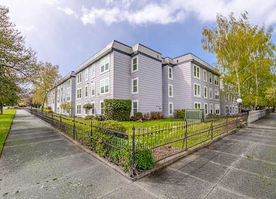 A grey apartment building with a black fence in front.