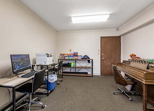 A room with a desk, chairs, and a computer.