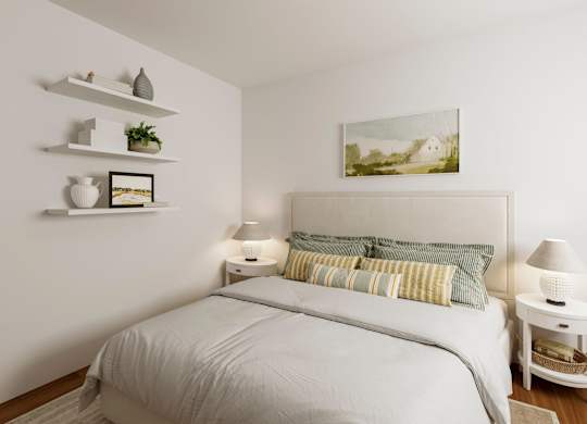 A white bedroom with a large bed and a painting on the wall.