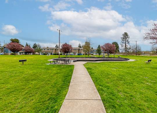 A park with a concrete walkway and green grass.