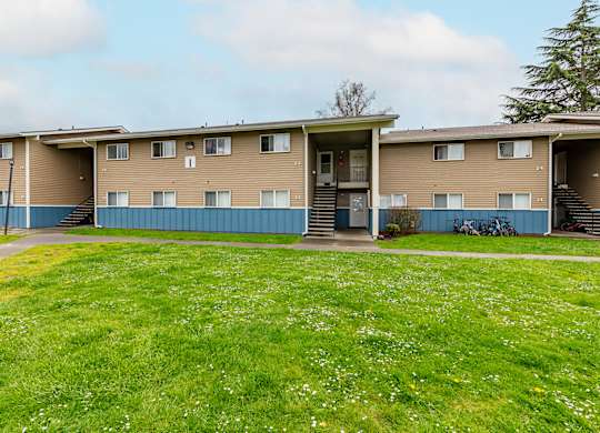 A row of apartment buildings with green grass in front.