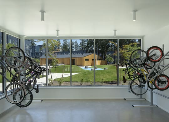 a room with bikes hanging on the wall and a large window with a view of a yard