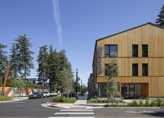 a city street with a yellow building on the left and trees on the right
