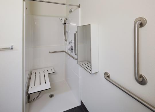 A white shower stall with a bench and grab bars.