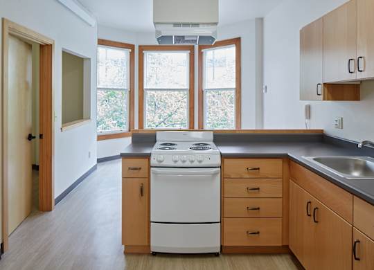 A kitchen with a white stove and wooden cabinets.