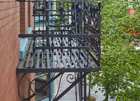 A balcony with a metal railing and a brick wall.