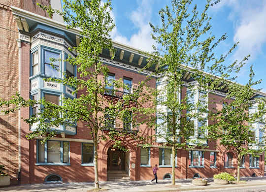 A red brick building with a green tree in front.