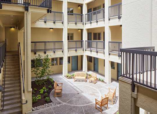 A courtyard with a bench and a tree in the middle of it.