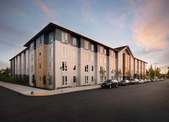 A modern apartment building with a parking lot in front.