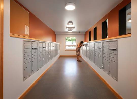 A woman walks down a hallway with lockers on both sides.