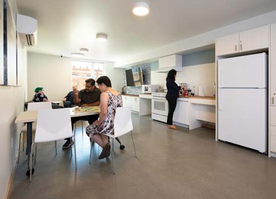A group of people are gathered around a table in a kitchen.