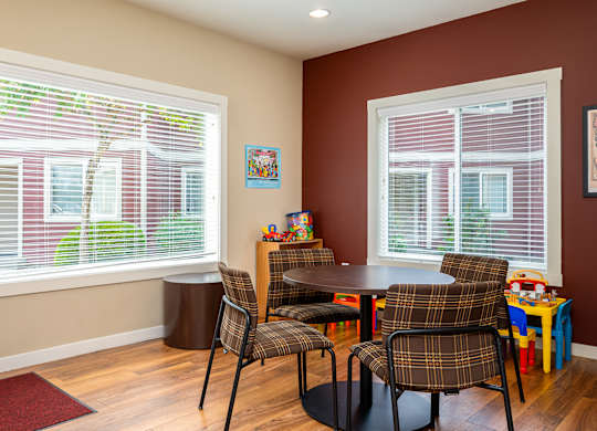 A room with a table and chairs and a window with blinds.