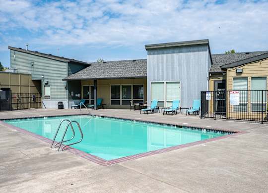 A swimming pool with a diving board in front of a building.