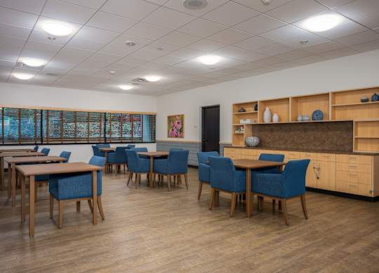 A room with tables and chairs and a cabinet with drawers.