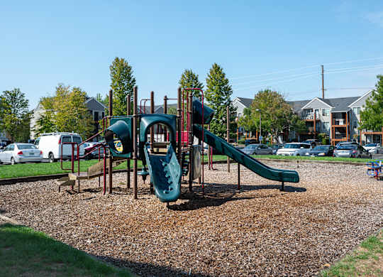 A playground with a green slide and a red and green play structure.