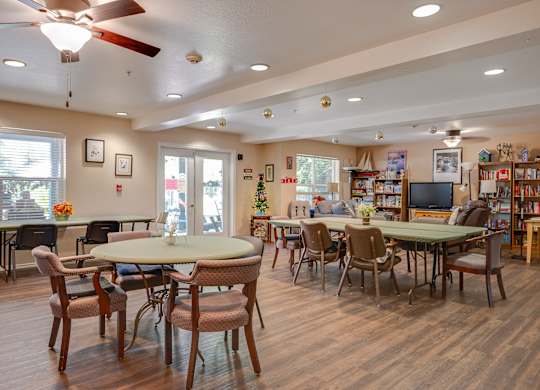A room with a white ceiling and a fan, with a dining table and chairs in the foreground.
