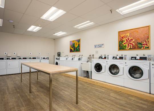 A laundromat with a long table in the middle and washing machines on both sides.
