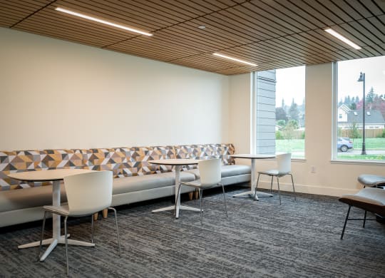 a lounge area with tables and chairs and a large window