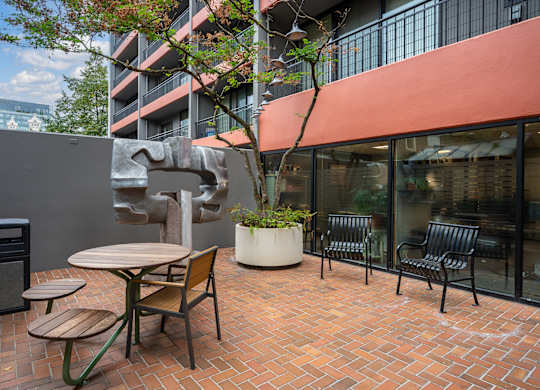 A patio with a table and chairs and a bench outside a building.