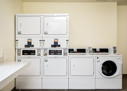 a row of washers and dryers in a laundry room