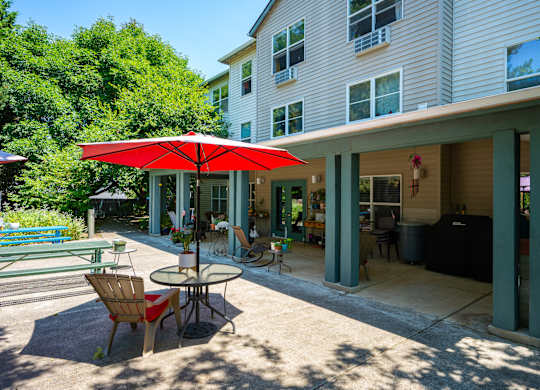 A patio with a table and chairs under a red umbrella.