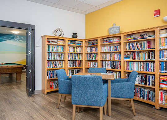A room with a pool table and a bookshelf filled with books.