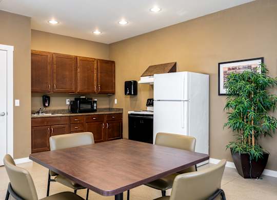 A kitchen with a table and chairs in the foreground and a refrigerator in the background.