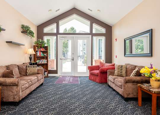 A living room with a couch, chair, and a potted plant.