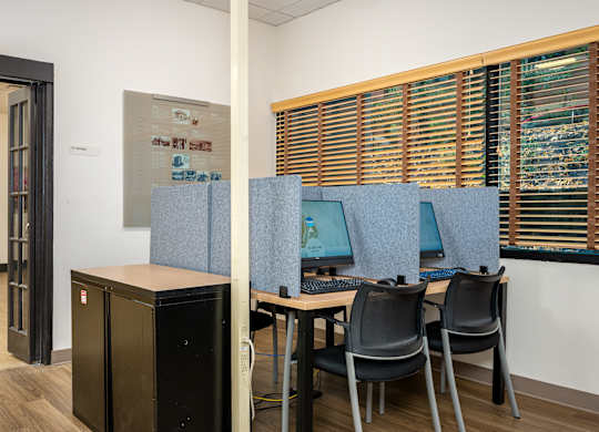 A room with a desk, chairs and a computer.