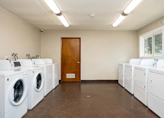 A laundromat with a row of washers and a door.