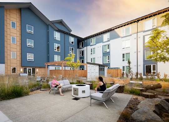 Two people sitting on chairs in front of a building.