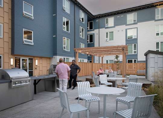 A man in a pink shirt is standing on a patio.