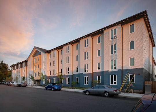 A row of modern apartment buildings with cars parked in front.