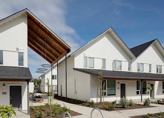 A modern white house with a brown roof and a black door.