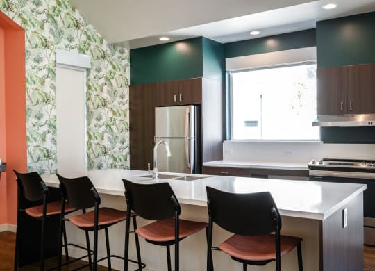 a kitchen with a white counter top and black chairs