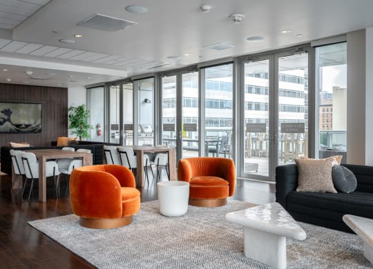 a living room with orange chairs and a table with a couch