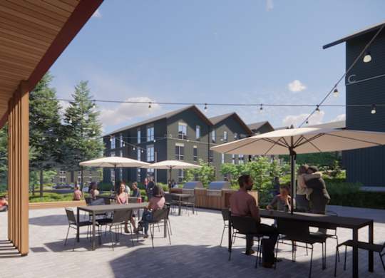 A group of people are sitting at tables under umbrellas on a patio.