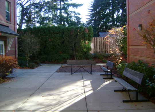 a patio with two benches and a table in a courtyard