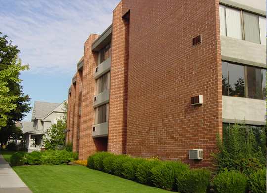 A red brick building with a green lawn in front.