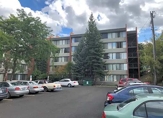A parking lot with cars and a building in the background.