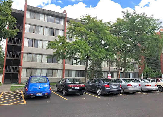 A blue car is parked in a parking lot in front of a building.