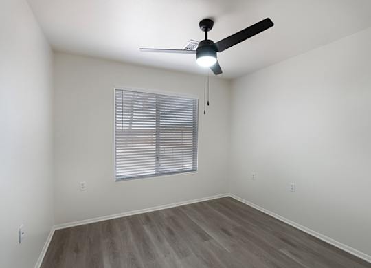 A room with a ceiling fan and a window with blinds.