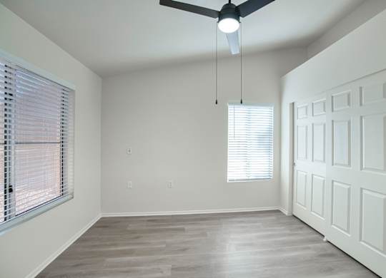 A room with a ceiling fan and a door.