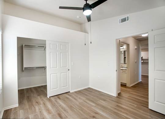 A room with a ceiling fan and a door leading to another room.
