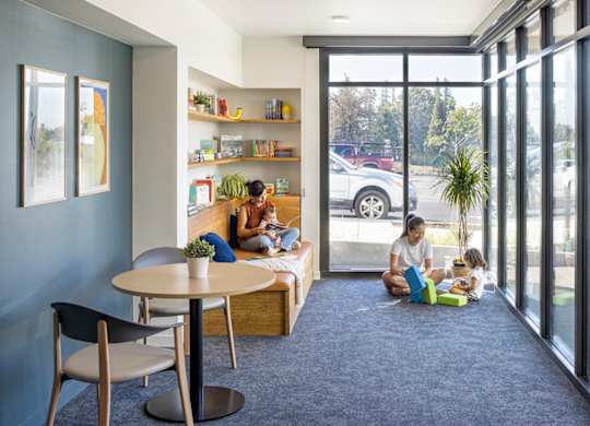 A family is sitting on the floor in a room with a large window.